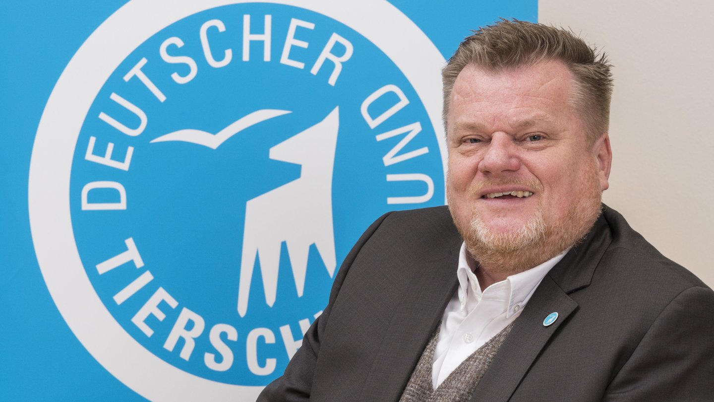 Tierschutzbund-Präsident Thomas Schröder sitzt vor dem Logo des Deutschen Tierschutzbundes