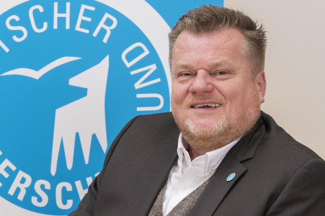Tierschutzbund-Präsident Thomas Schröder sitzt vor dem Logo des Deutschen Tierschutzbundes
