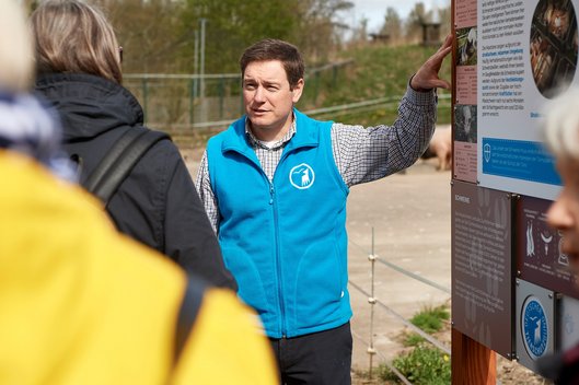 Patrick Boncourt bei einer Führung vor einem Schild im Tierschutzzentrum Weidefeld