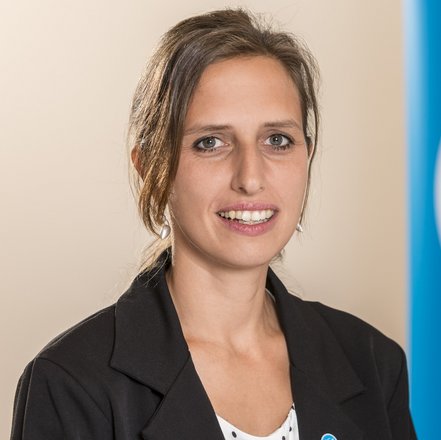 Porträt von Caroline Steinhardt, die vor dem Logo des Deutschen Tierschutzbundes sitzt